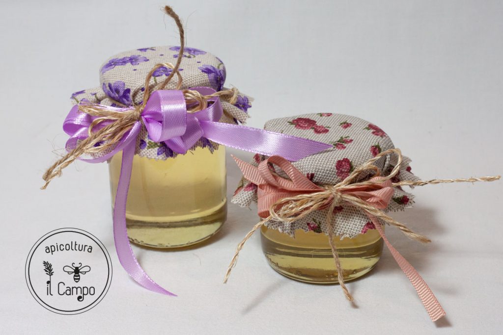 Vasetti in due formati con miele di acacia e stoffa tela grezza con fiorellini viola o rosa.
